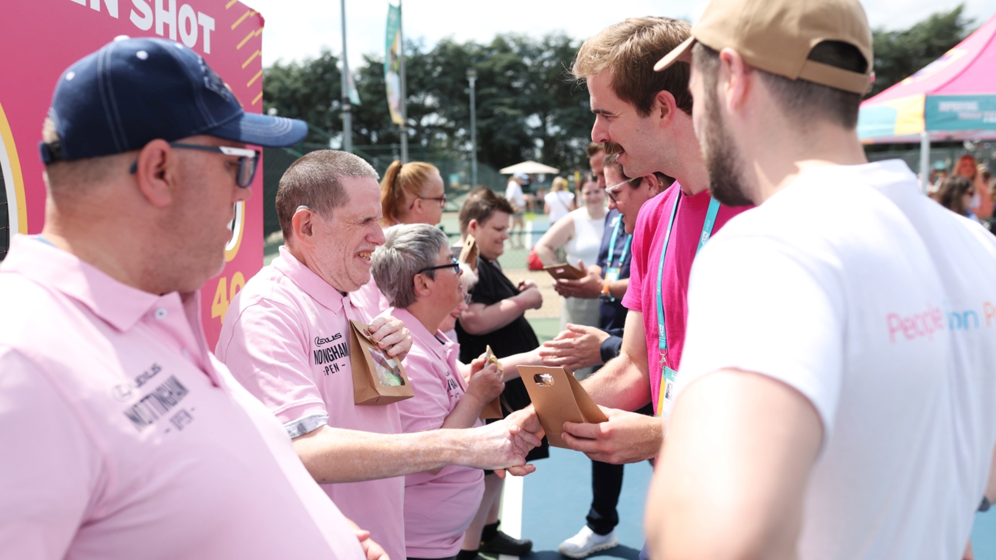 Two lines of people looking at each other shaking hands and presenting a small gift