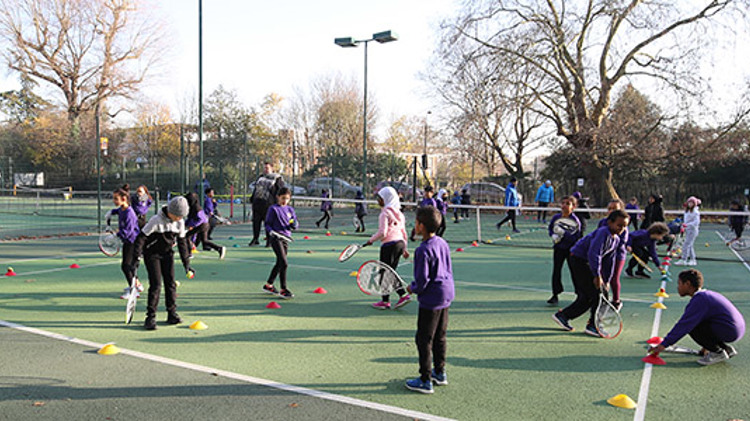 School children playing tennis  on outdoor courts