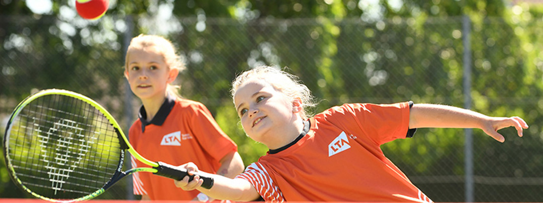 A child hitting a tennis ball as part of the tennis for kids programme