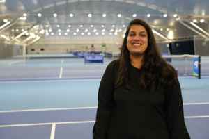 LTA colleague Fizza Abid standing in front of the indoor hard courts at the National Tennis Centre