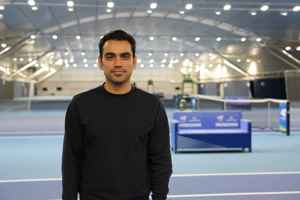 LTA colleague Samy Jatoi standing in front of the indoor hard courts at the National Tennis Centre