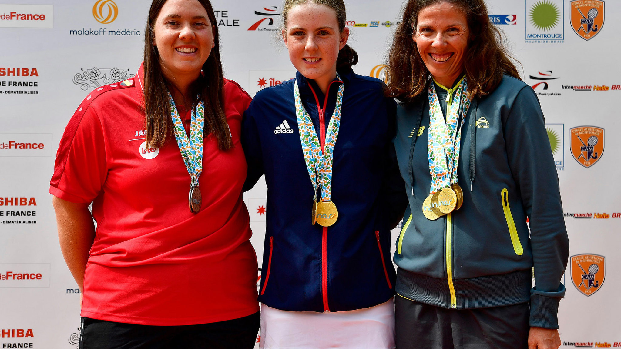 Anna Mcbride wearing her medal posing with two other players