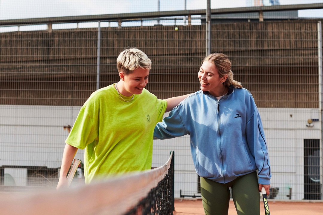 Two women patting each other on the back over a net