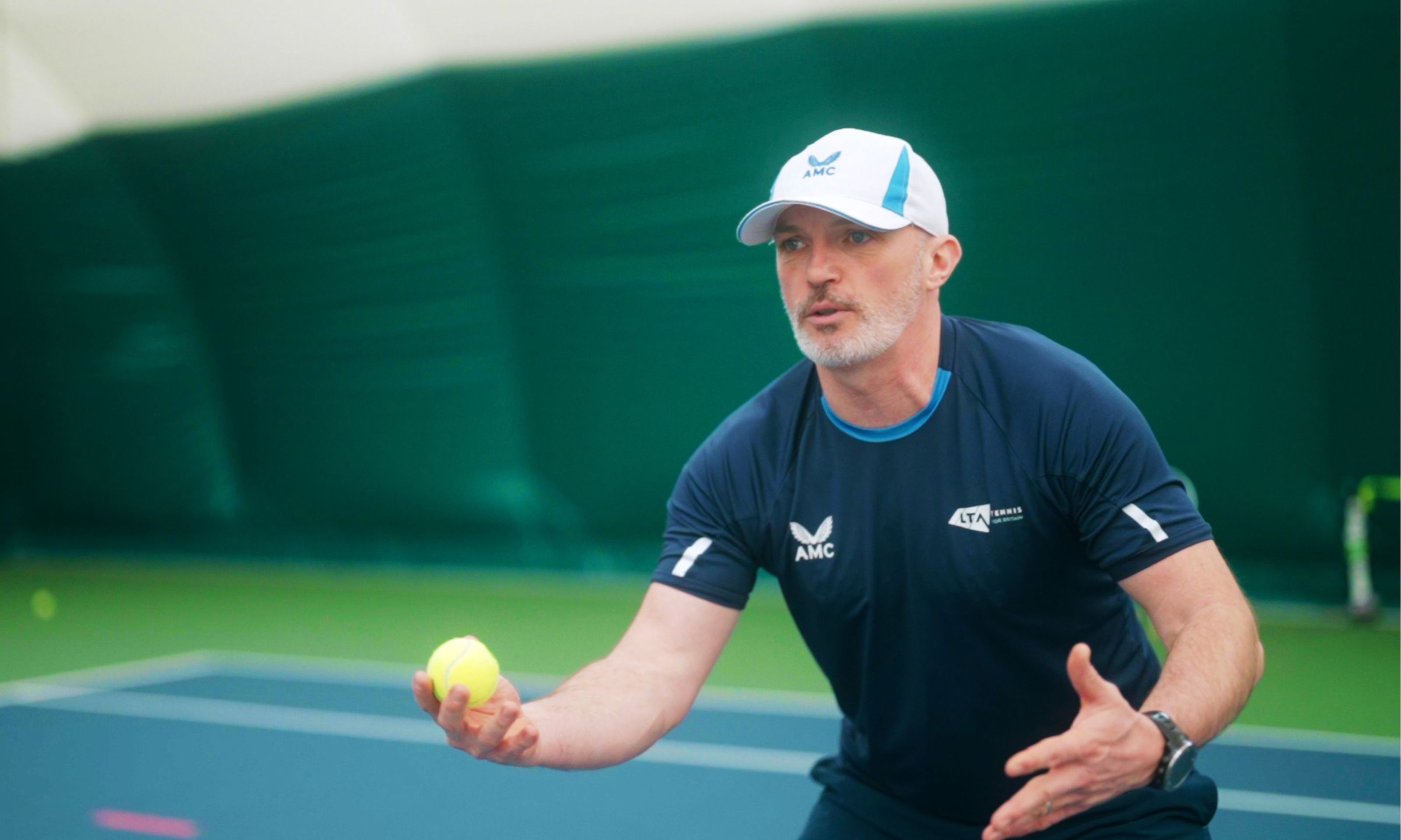 Coach, Shaun Dacon holding a tennis ball, during a session