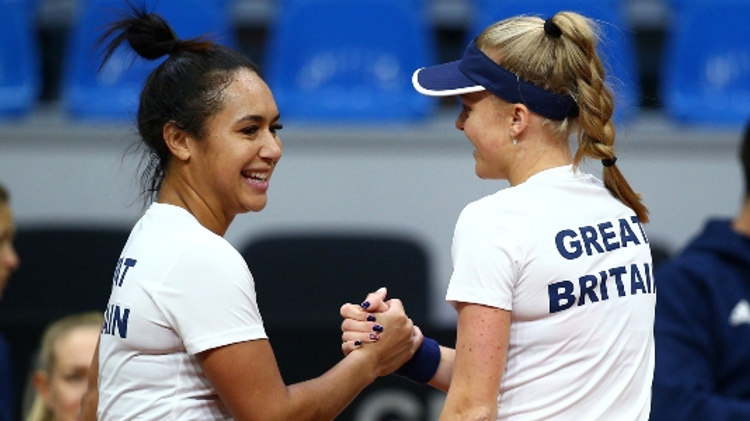 Heather Watson and Harriet Dart shaking hands and smiling in front of people blurred out in the background