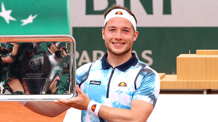 Alfie Hewett holding a trophy on a tennis court