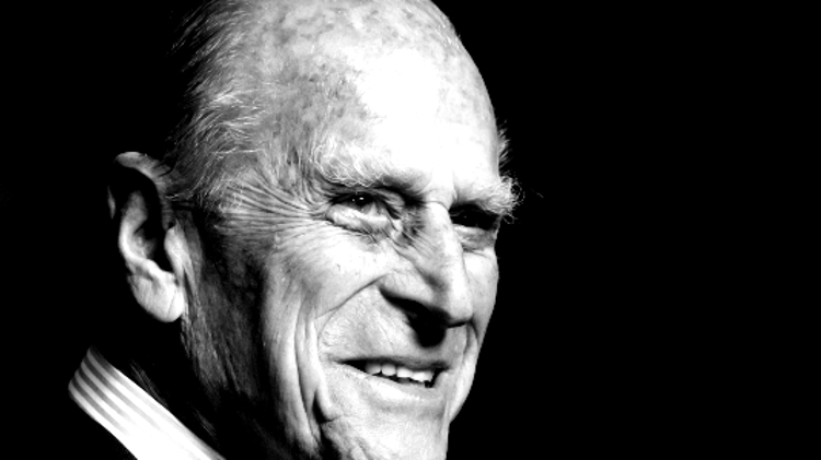 A black and white headshot of Prince Philip smiling