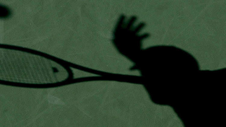 Shadow of a tennis player on a green court