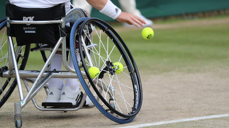 Wheelchair tennis player bouncing a tennis ball