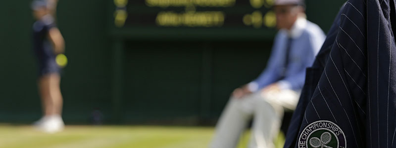 Blurry picture of court with focus on wimbledon badge on officials jacket