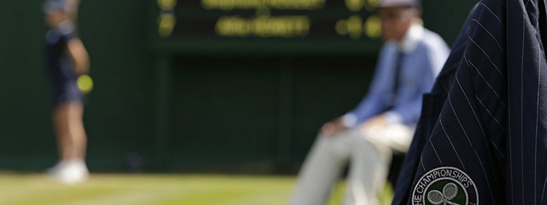 Blurry picture of court with focus on wimbledon badge on officials jacket