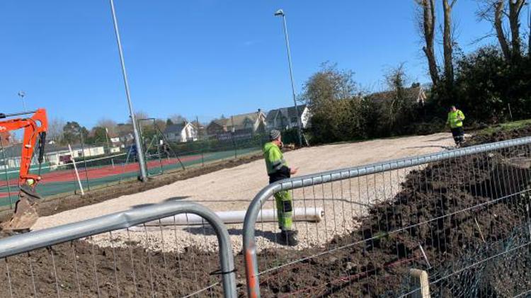 A construction site in front of tennis courts