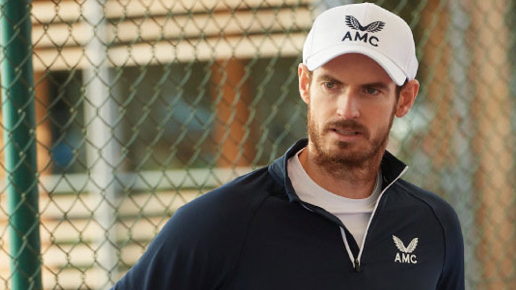 close up image of andy murray on court wearing amc branded jumper and hat
