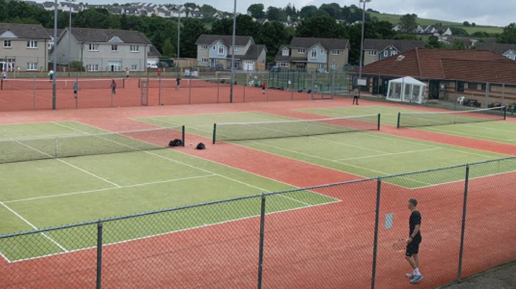 image of grass tennis courts at brought ferry tennis club with two players  playing a match on one of the courts
