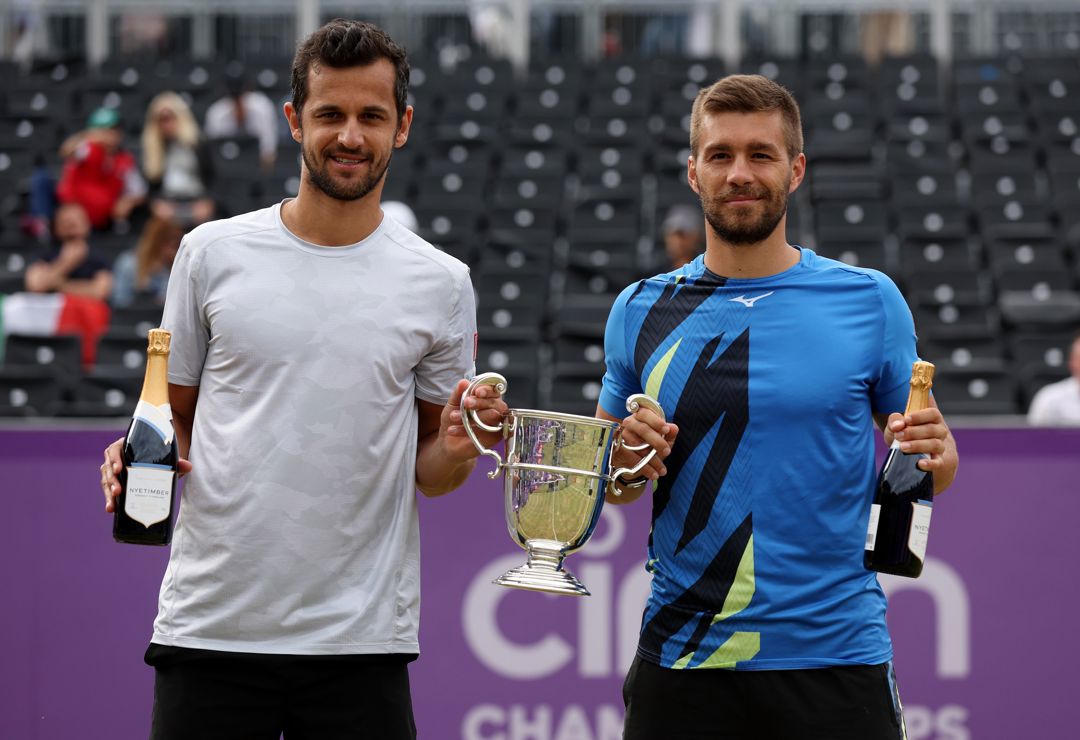 Two male players with a trophy and a champagne bottle