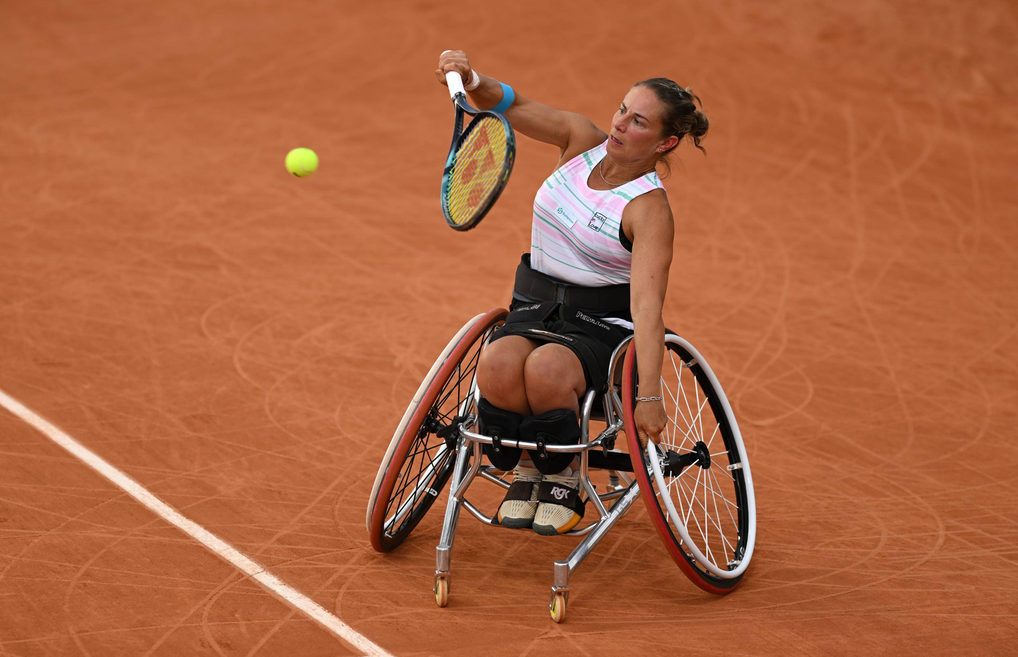 Wheelchair tennis player Lucy Shuker hitting a backhand on a clay court while sat in her wheelchair 