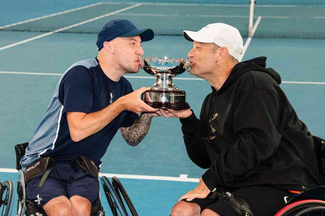 Andy Lapthorne and David Wagner kissing their quad doubles trophy on court at the Australian Open
