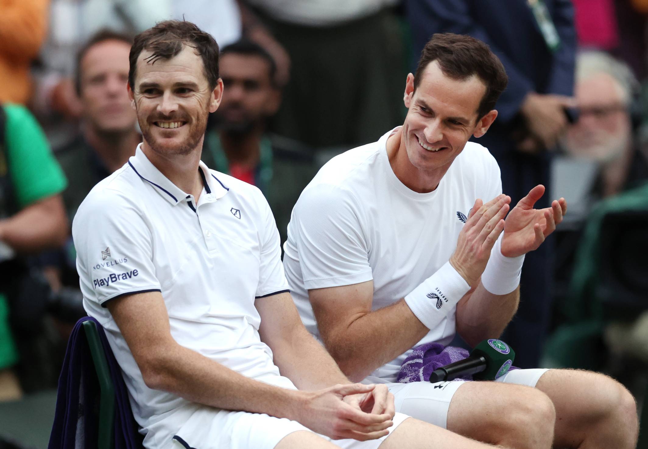 Jamie and Andy Murray laugh on court after their first round Wimbledon doubles match