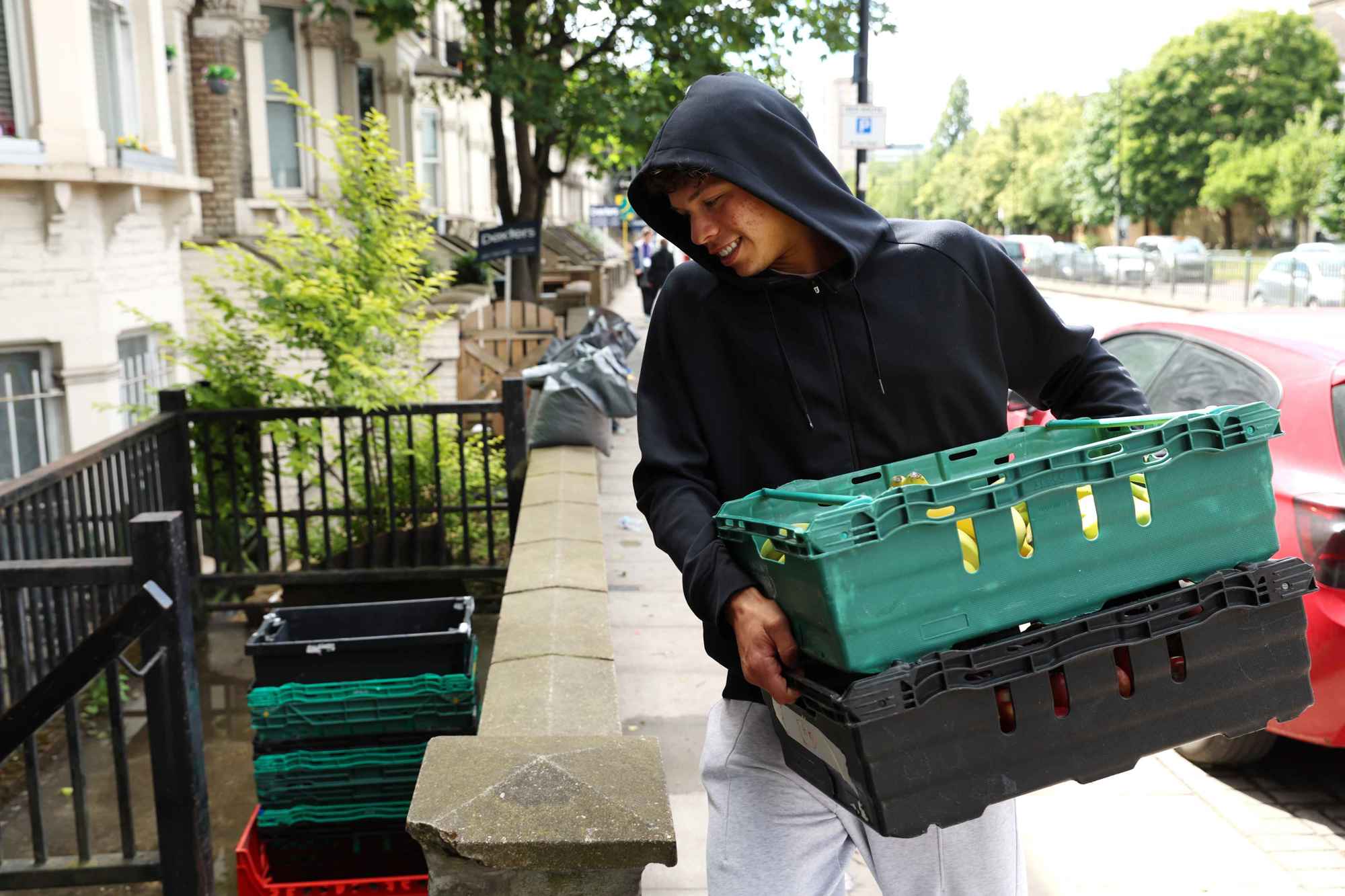 Ben Shelton walking along the street while carrying a box of food to donate to the food bank