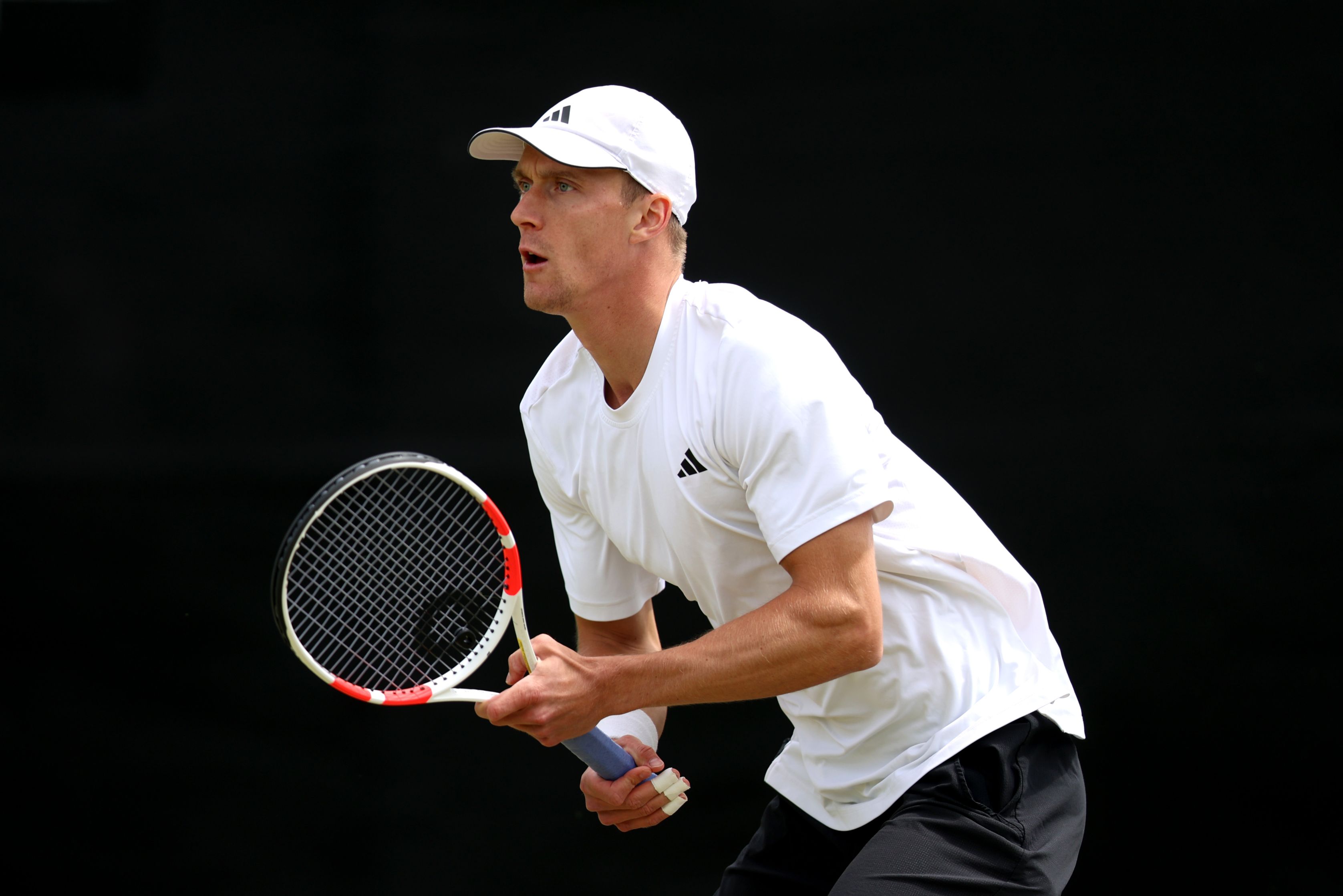 British tennis player holding his tennis racket and preparing to return a serve on court