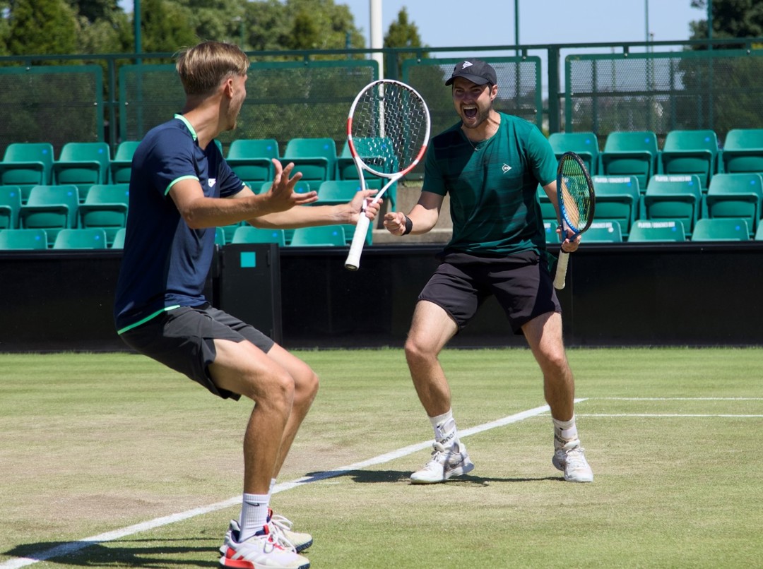Two men playing tennis on a grass court celebrate