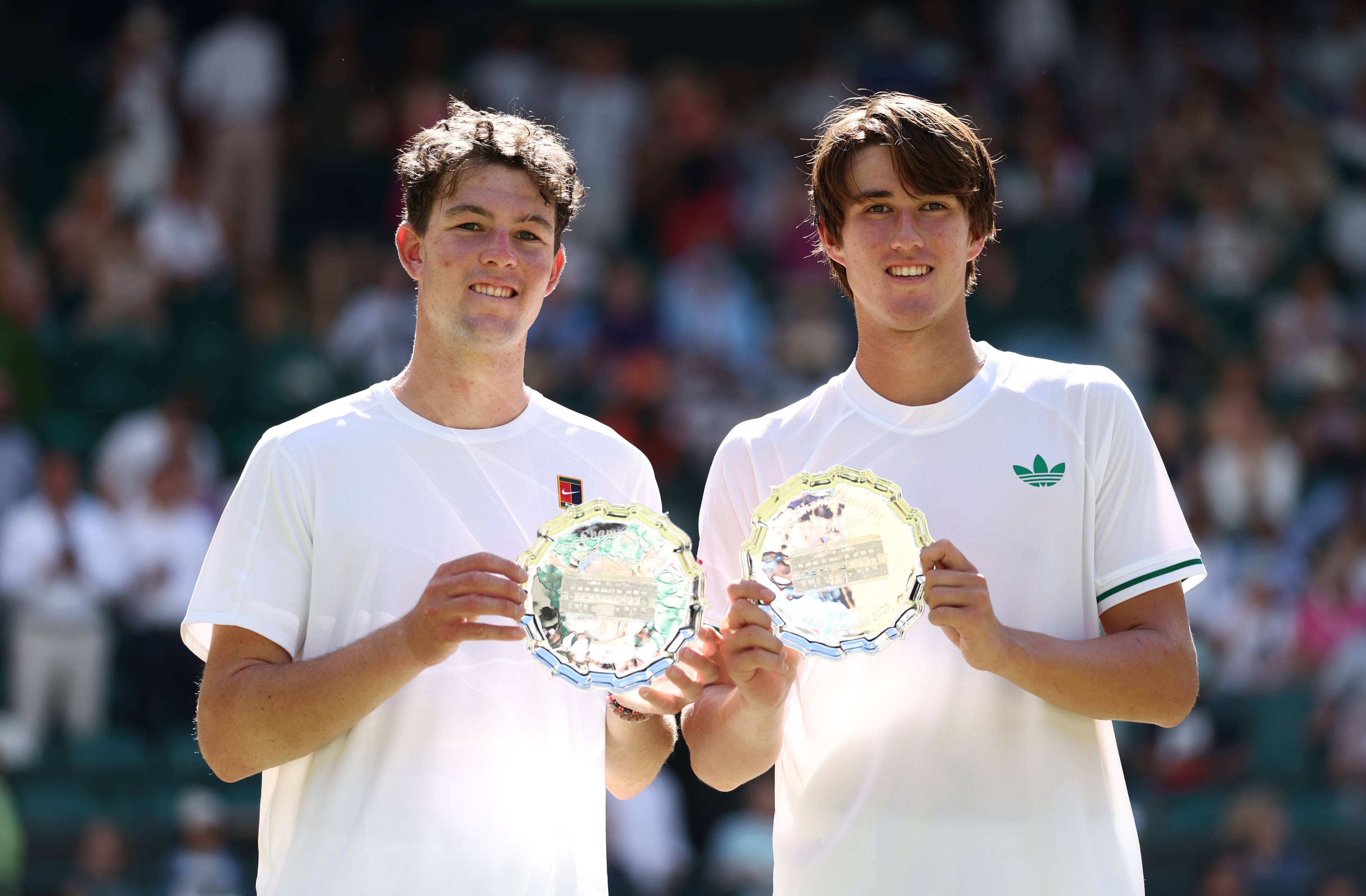 Oliver Bonding and Jagger Leach smile and hold up their boy's doubles runner-up trophy at Wimbledon