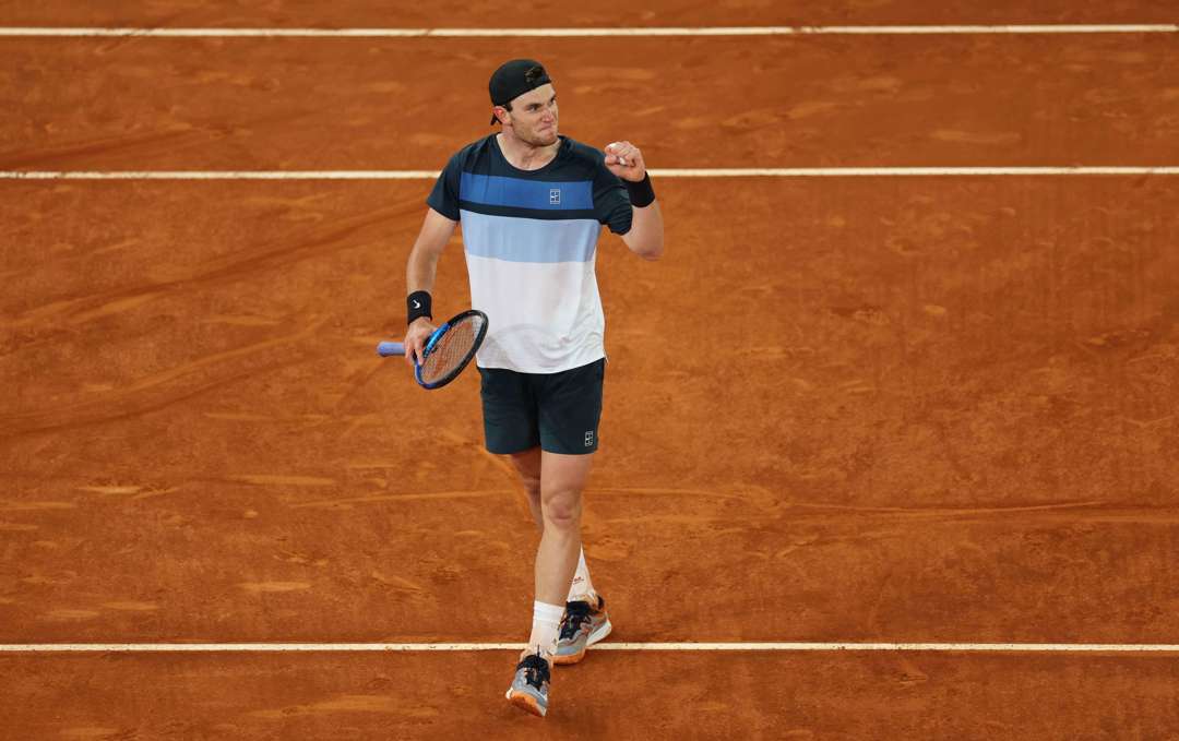 Jack Draper stood on a clay court at the Mutua Madrid Open while clenching his fist and holding his tennis racket