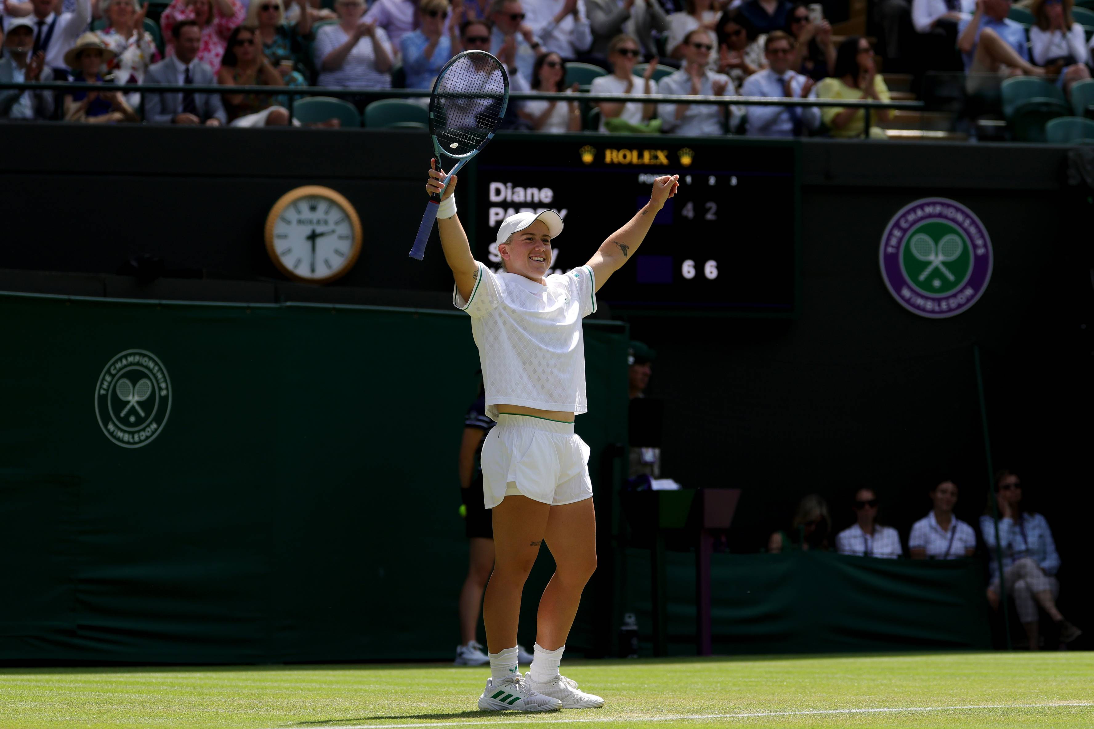 Sonay Kartal holding her hands up in the air with her tennis racket in one hand after beating Diane Parry at Wimbledon 