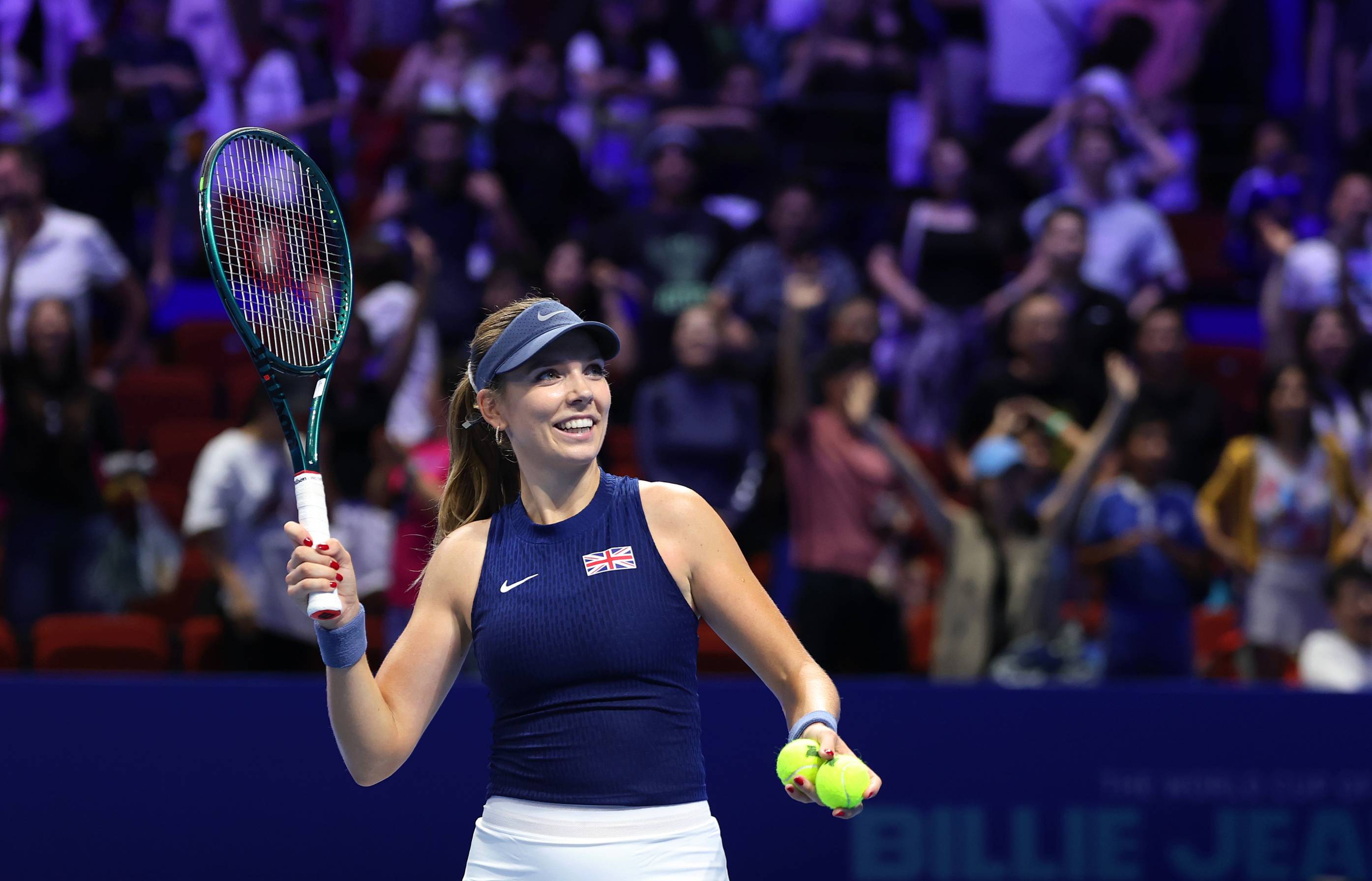 British tennis player Katie Boulter smiling while holding her racket in the air at the Billie Jean King Cup Finals in Shenzhen