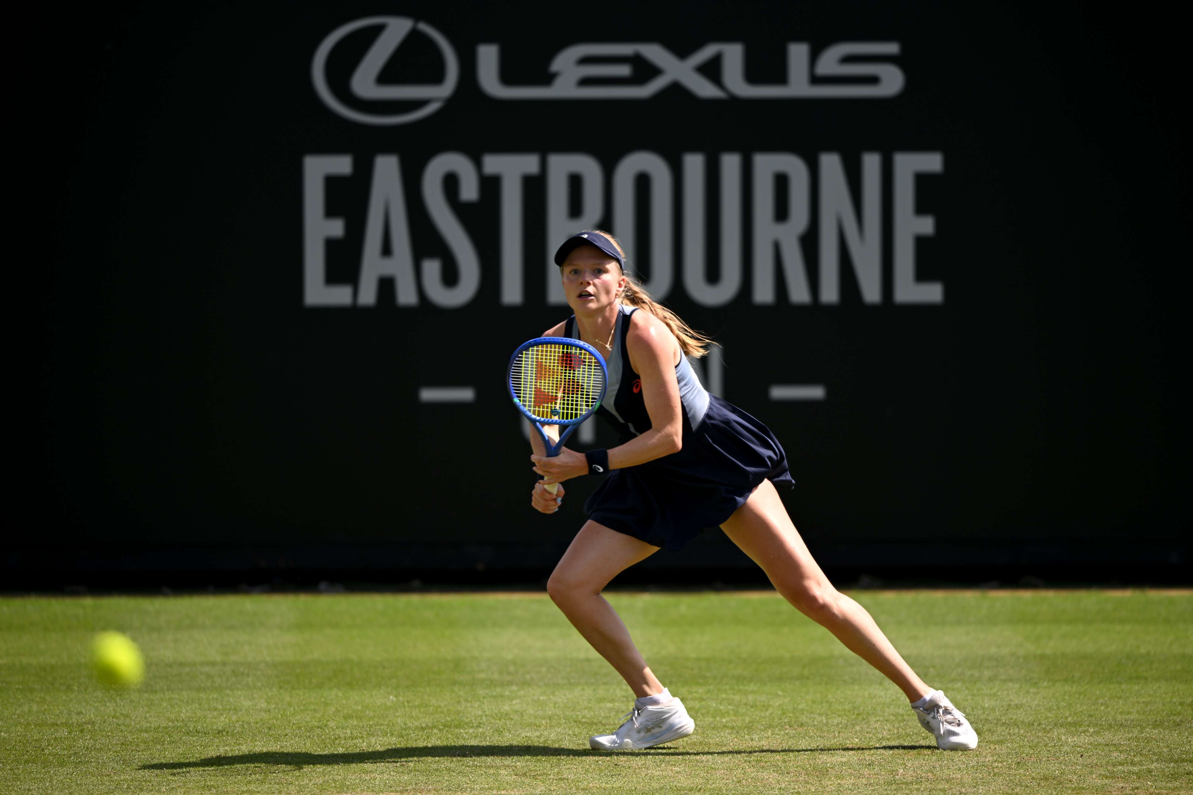 Harriet Dart preparing to run and hit a ball on a grass court