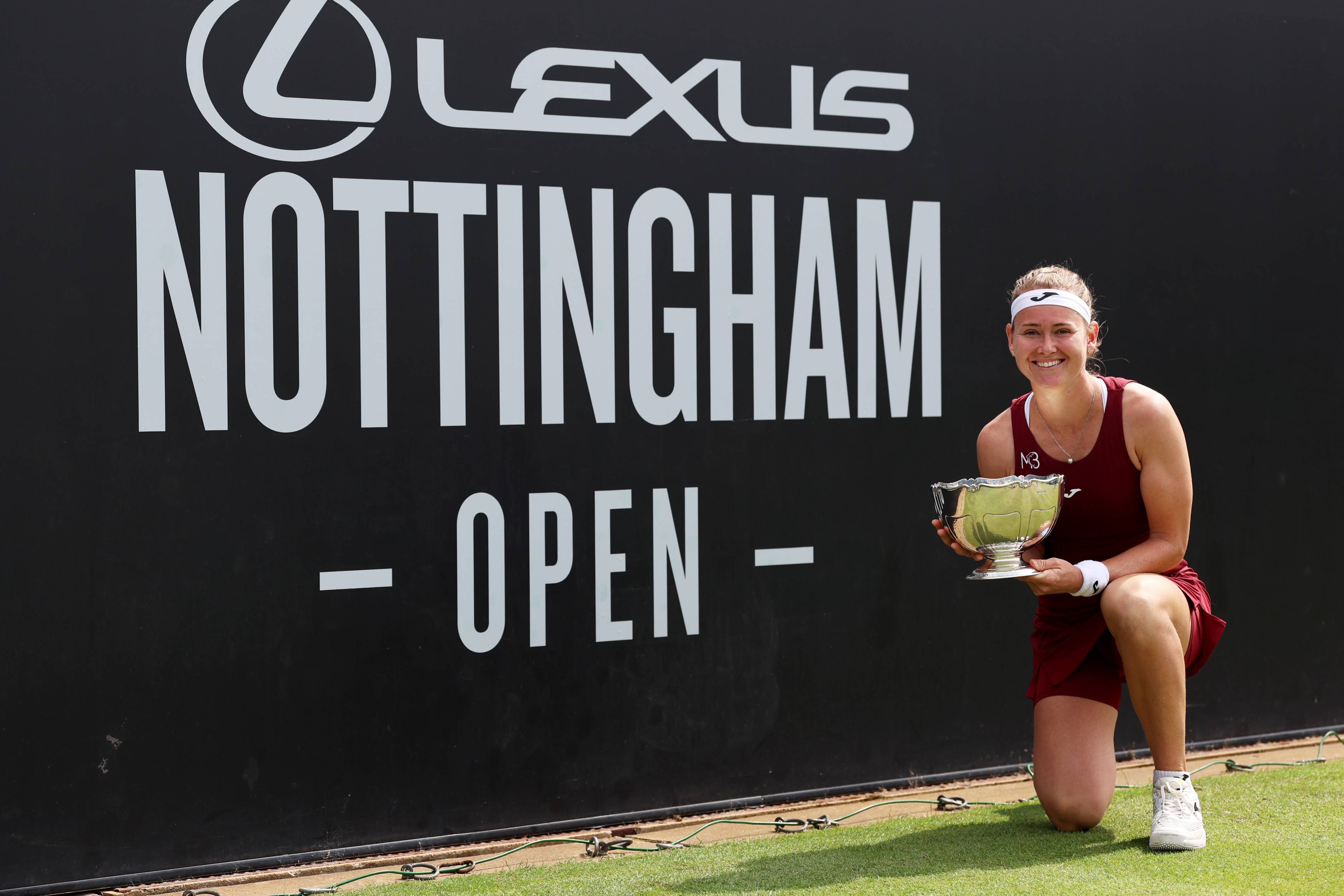 Maria Bouzkova crouching down and holding her Lexus Nottingham Open winners trophy 