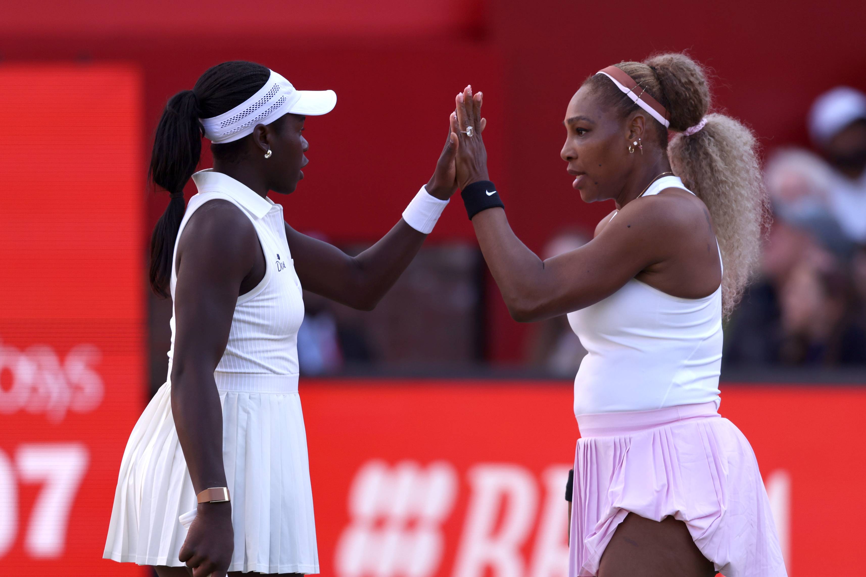 Serena Williams and Victoria Mboko high-fiving on court after winning their first round doubles match at the HSBC Championships 