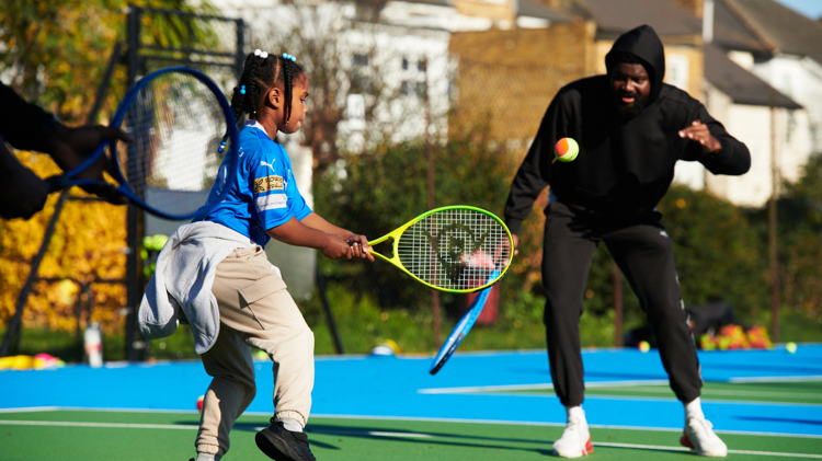 A young girl hitting a ball with a racket at a Free Park Tennis session