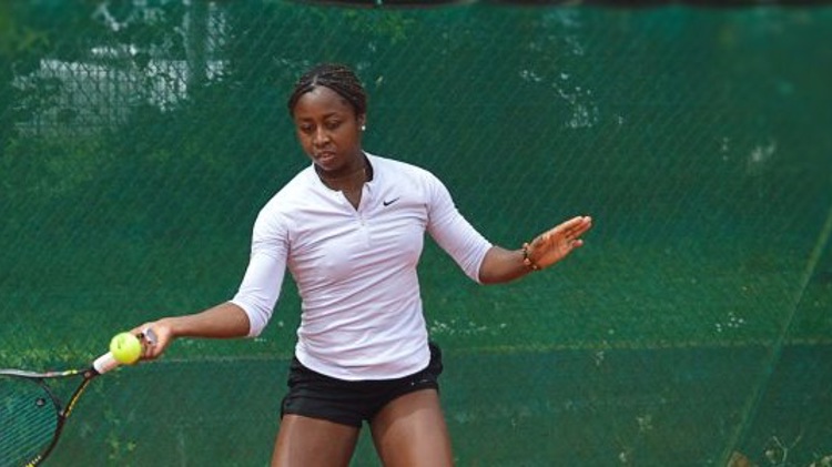 Woman playing tennis with a person in the background