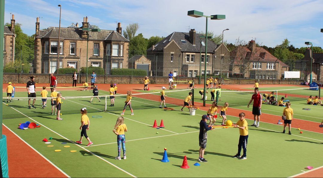 Children playing on a busy tennis court
