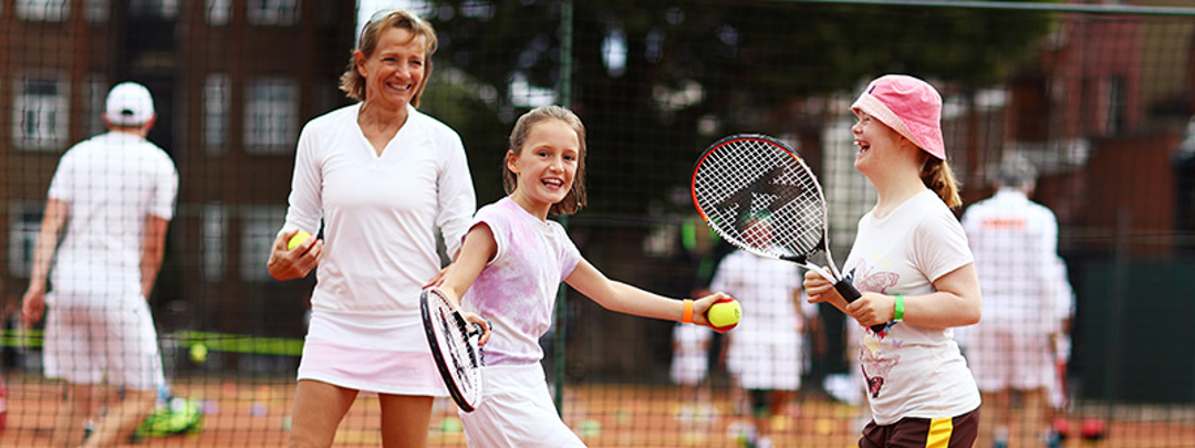 Young girls smiling and laughing playing tennis