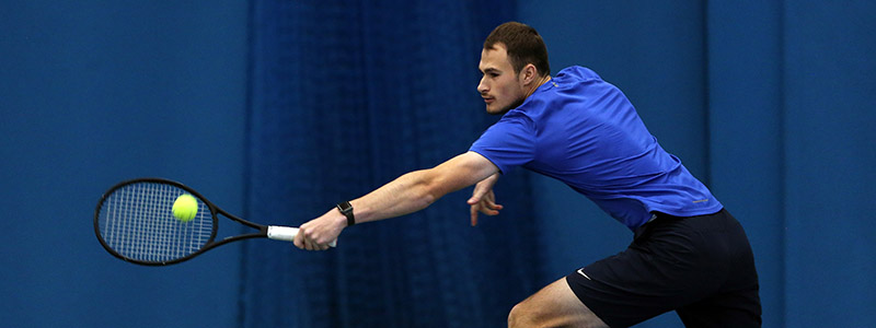 adult player on court reaching out to hit a ball
