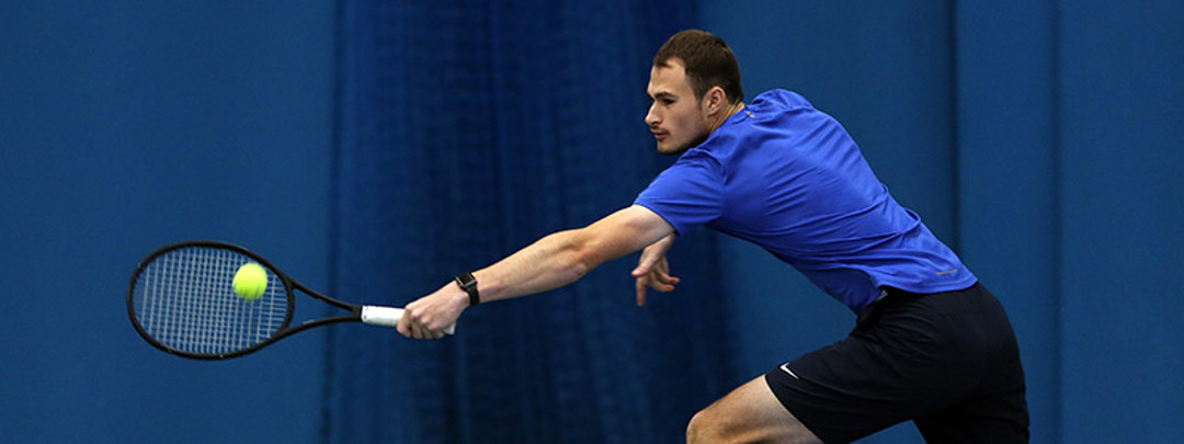 adult player on court reaching out to hit a ball
