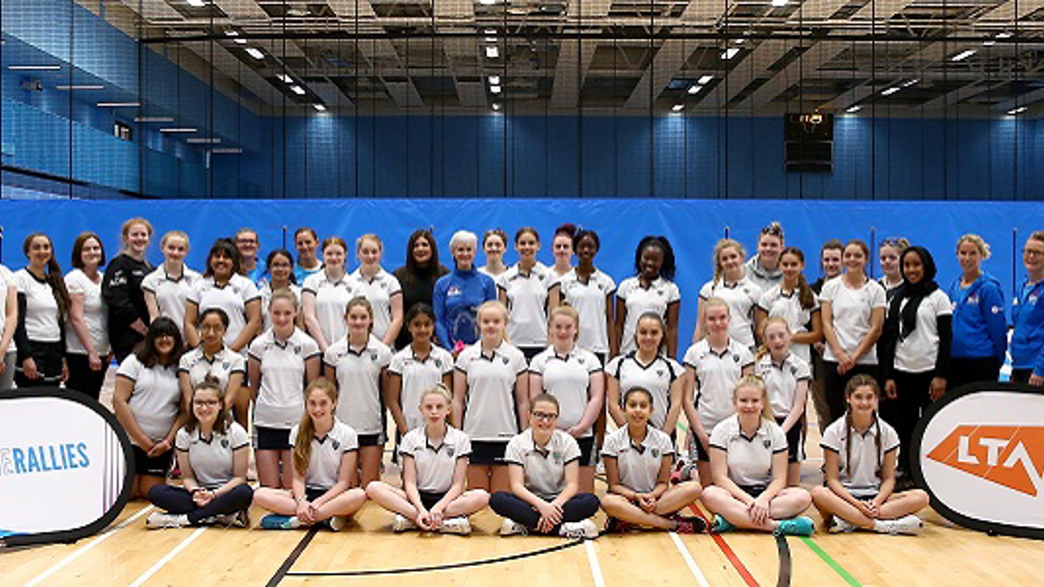 Judy Murray standing alongside girls tennis players smiling for a group picture with the LTA She Rallies banner