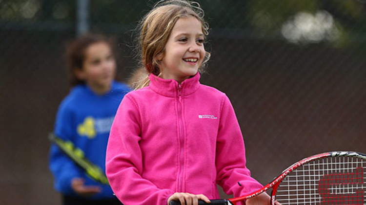 Young girl smiling and playing tennis