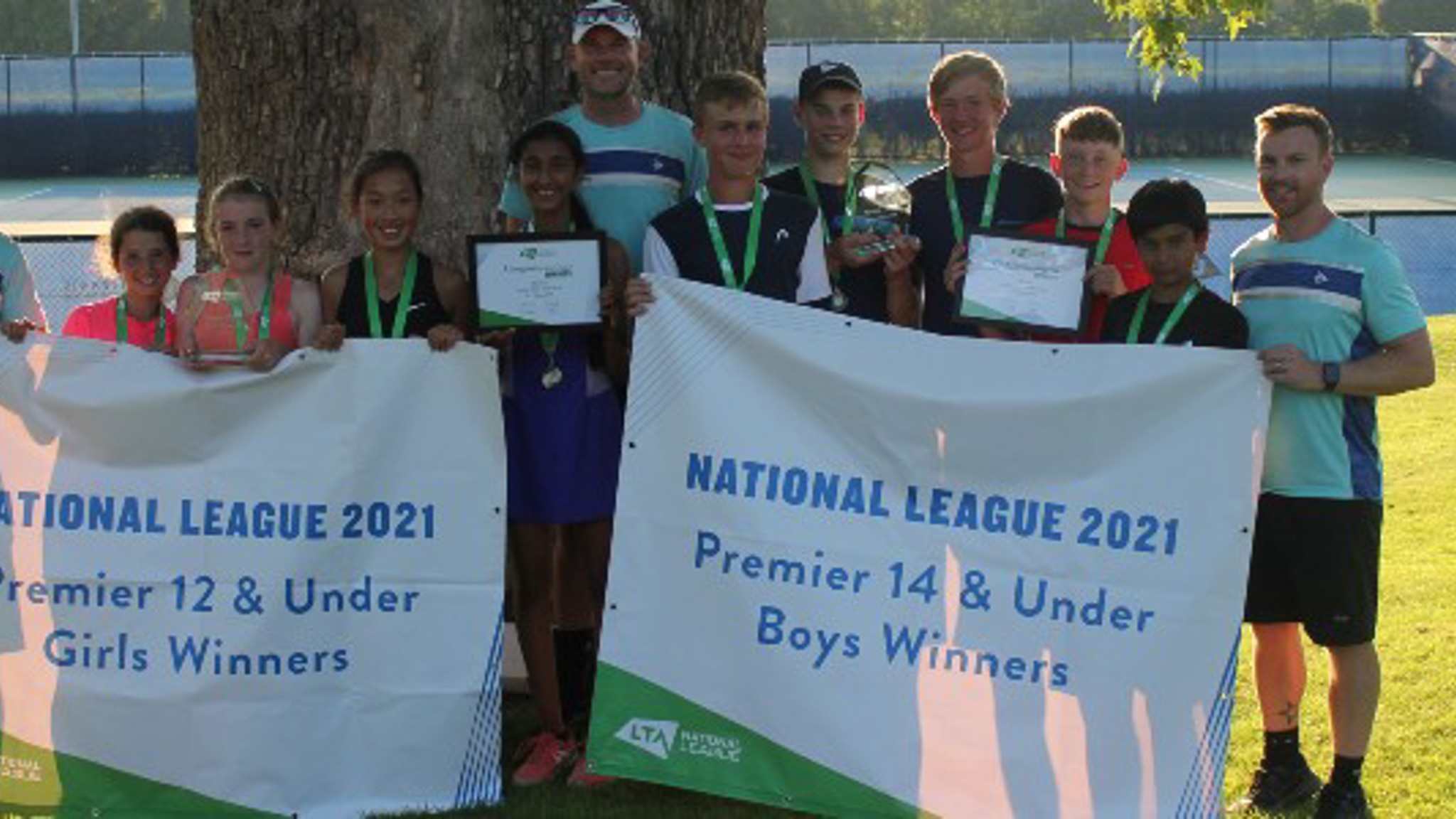 12U girls and 14U boys winning teams standing in a line holding the National League 2021 winners signs