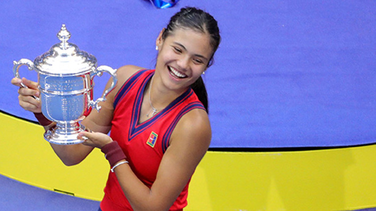 Emma Raducanu smiling and holding the 2021 US Open trophy