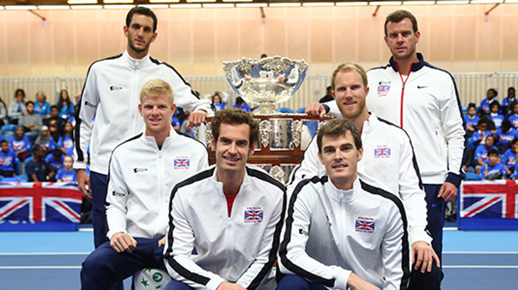 6 members of davis cup team standing and sitting around big silver trophy with GB flags at the bag