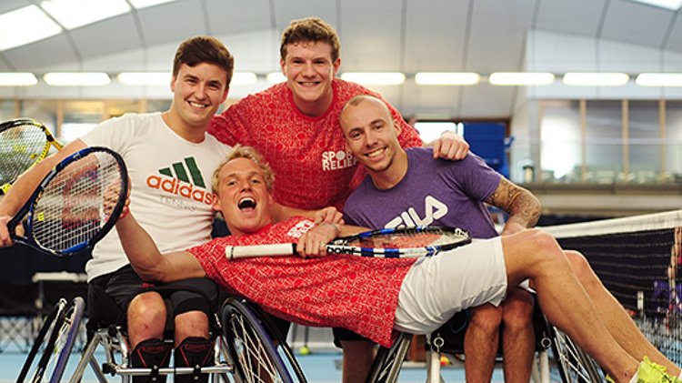 Jamie Laing laying across two wheelchair tennis players at the National Tennis Centre in London