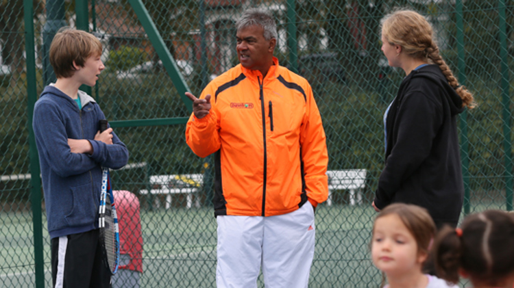 robby sukhdeo wearing orange jacket talking to players outside Albert Park court