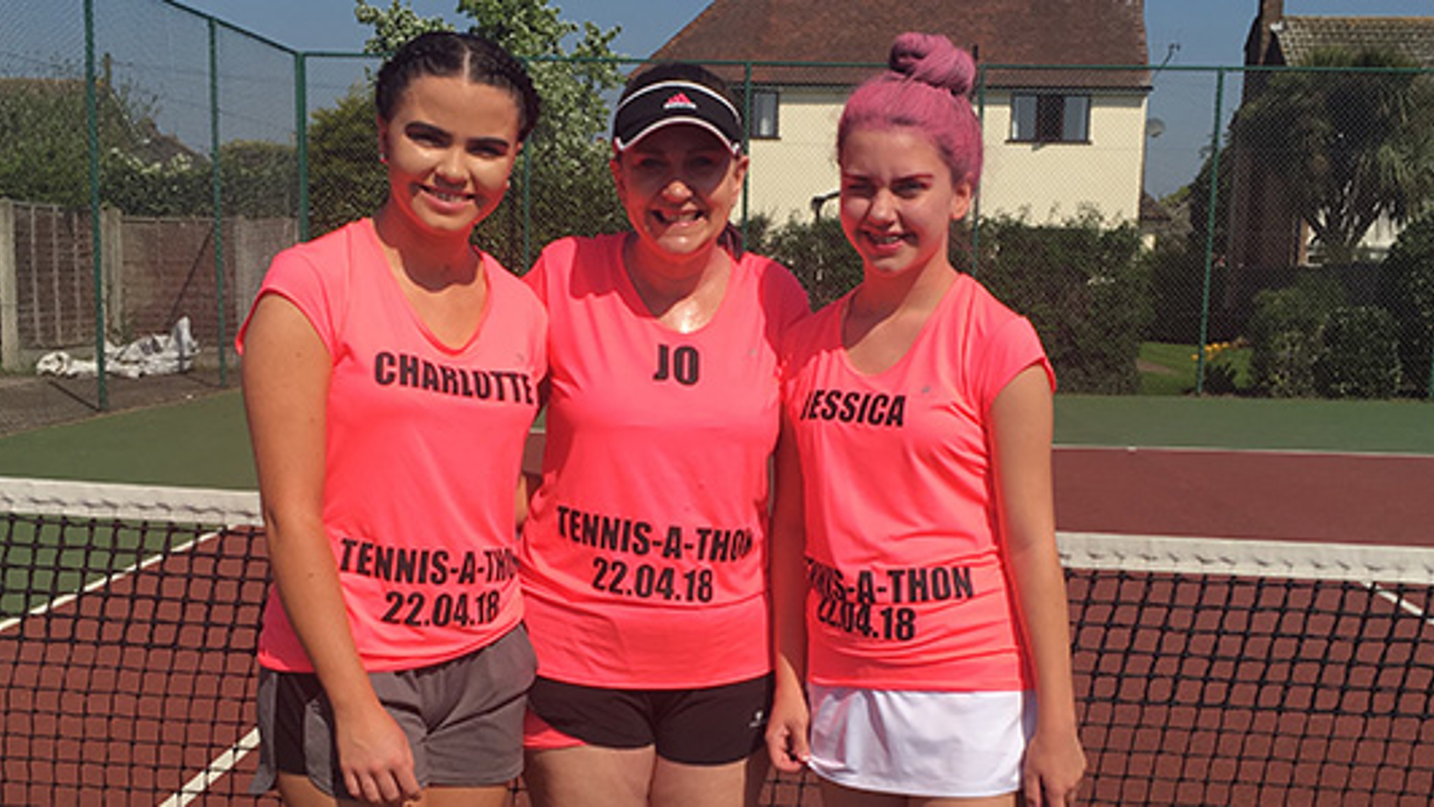 Jo Stehle standing on court with her two daughters wearing pink tennis-a-thon t-shirts