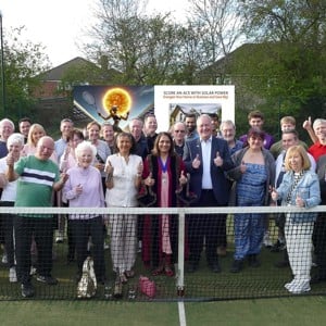 Members of Harrow Weald lawn tennis club posing with their thumbs up behind the net